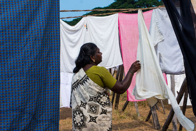 Woman holding clothes hanging on clothesline