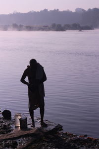 Rear view of man standing by lake