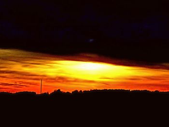 Silhouette landscape against dramatic sky during sunset