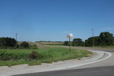 Empty road amidst field against clear sky