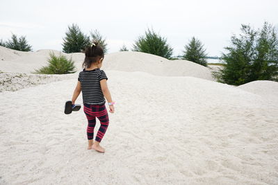 Rear view of woman walking on sand