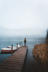 Rear view of man on pier against sky