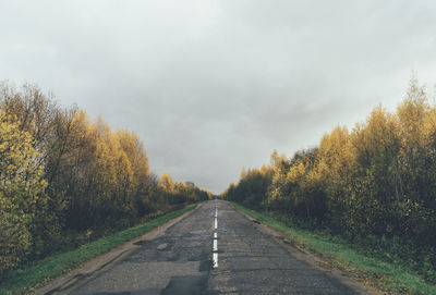 Road amidst trees against sky during autumn