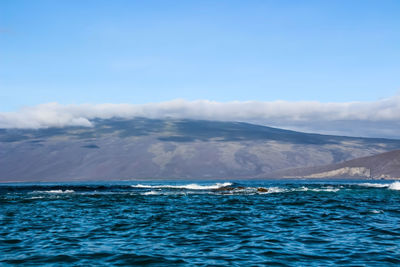 Scenic view of sea and mountains against blue sky