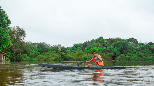 Man rowing boat in river against sky