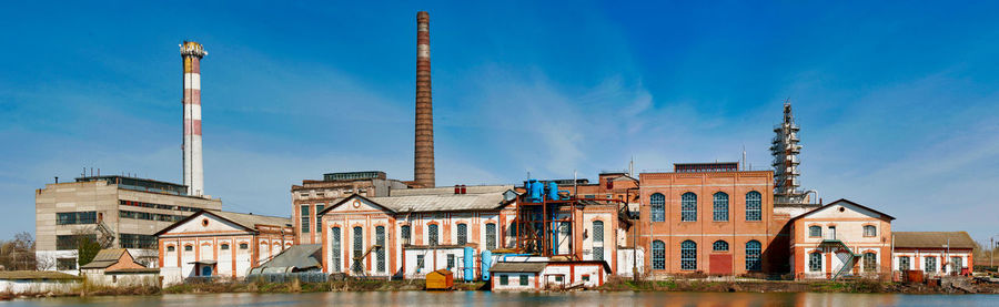 Buildings by river against blue sky