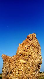 Low angle view of rock formation against clear blue sky