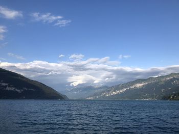 Scenic view of sea by mountains against sky