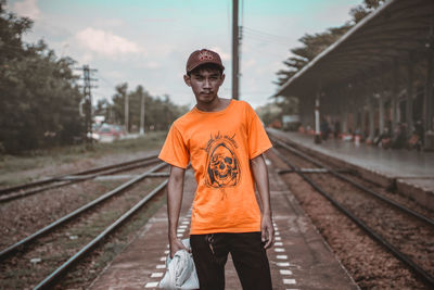 Man standing at railroad station against sky