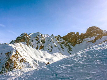 Scenic view of snowcapped mountains against blue sky