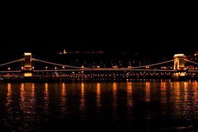 Illuminated bridge over river at night