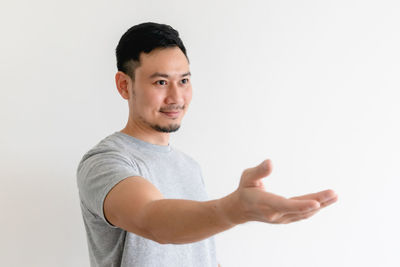 Portrait of young man standing against white background