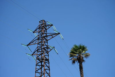 Low angle view of electricity pylon against clear blue sky