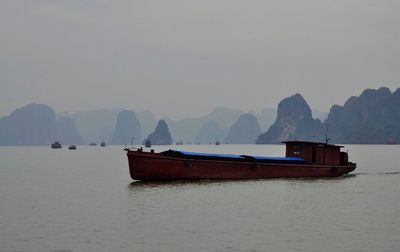 Boat on sea against mountains