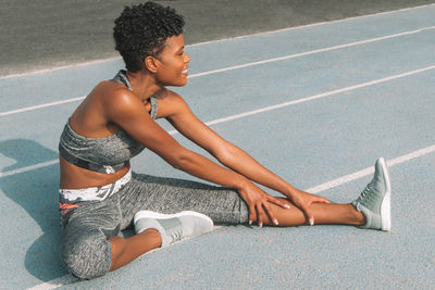 Side view of woman stretching leg on sports track