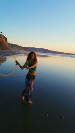 Portrait of woman standing on beach against clear sky