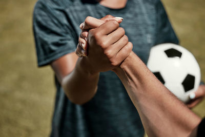 Midsection of man holding soccer ball