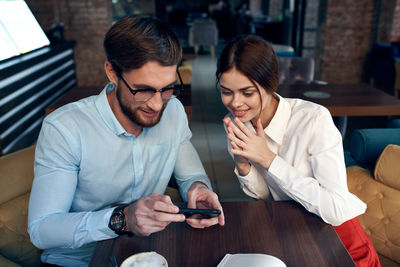 Young man using smart phone while sitting on table