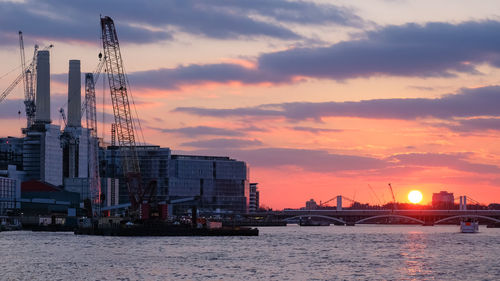 Commercial dock by sea against sky during sunset