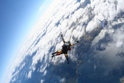 Aerial view of friends skydiving over clouds and landscape