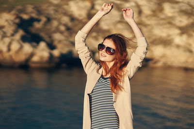 Woman wearing sunglasses standing against water