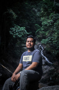 Young man sitting on rock in forest