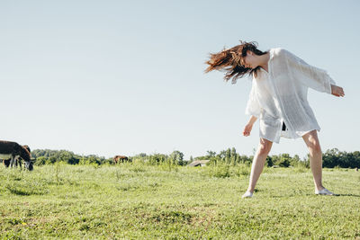 Woman with umbrella on field against sky