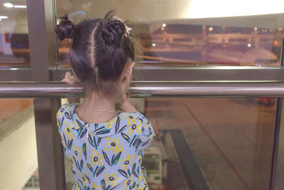 Rear view of woman looking through window