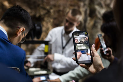 Businessman exhibiting 3d printer while colleagues filming through smart phones at convention center