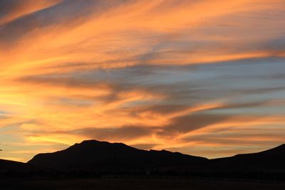Scenic view of silhouette mountains against dramatic sky