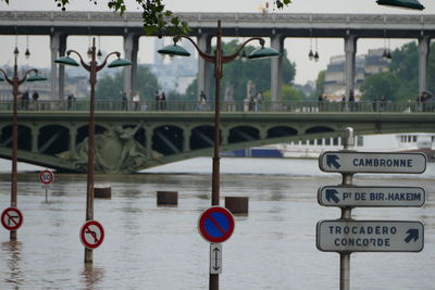 Road sign on bridge over river in city