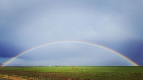 Scenic view of rainbow over field against sky