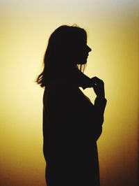 Side view of silhouette woman against yellow background