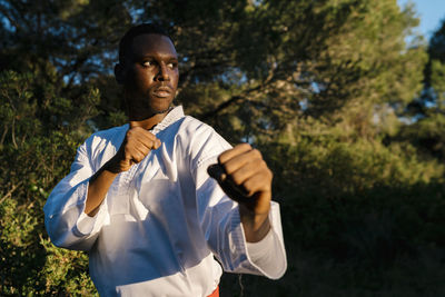 Portrait of teenage boy standing against trees