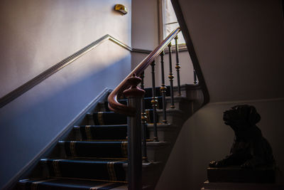 Low angle view of spiral staircase against wall at home with a dog sculpture and sunlight