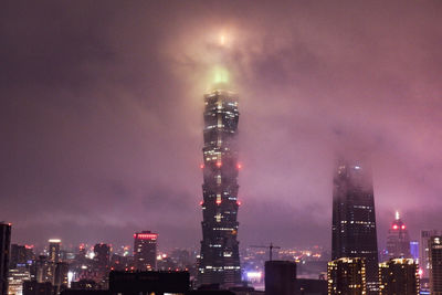 Illuminated buildings in city against sky at night