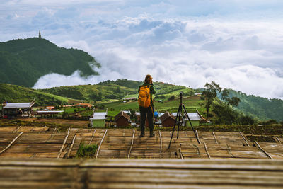 Rear view of woman photographing against landscape against cloudscape