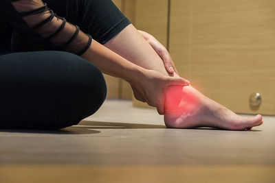Digital composite image of woman holding foot in pain on floor