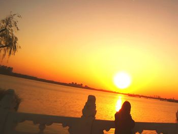 Silhouette people on beach against clear sky during sunset