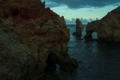 Rock formations on sea shore against sky