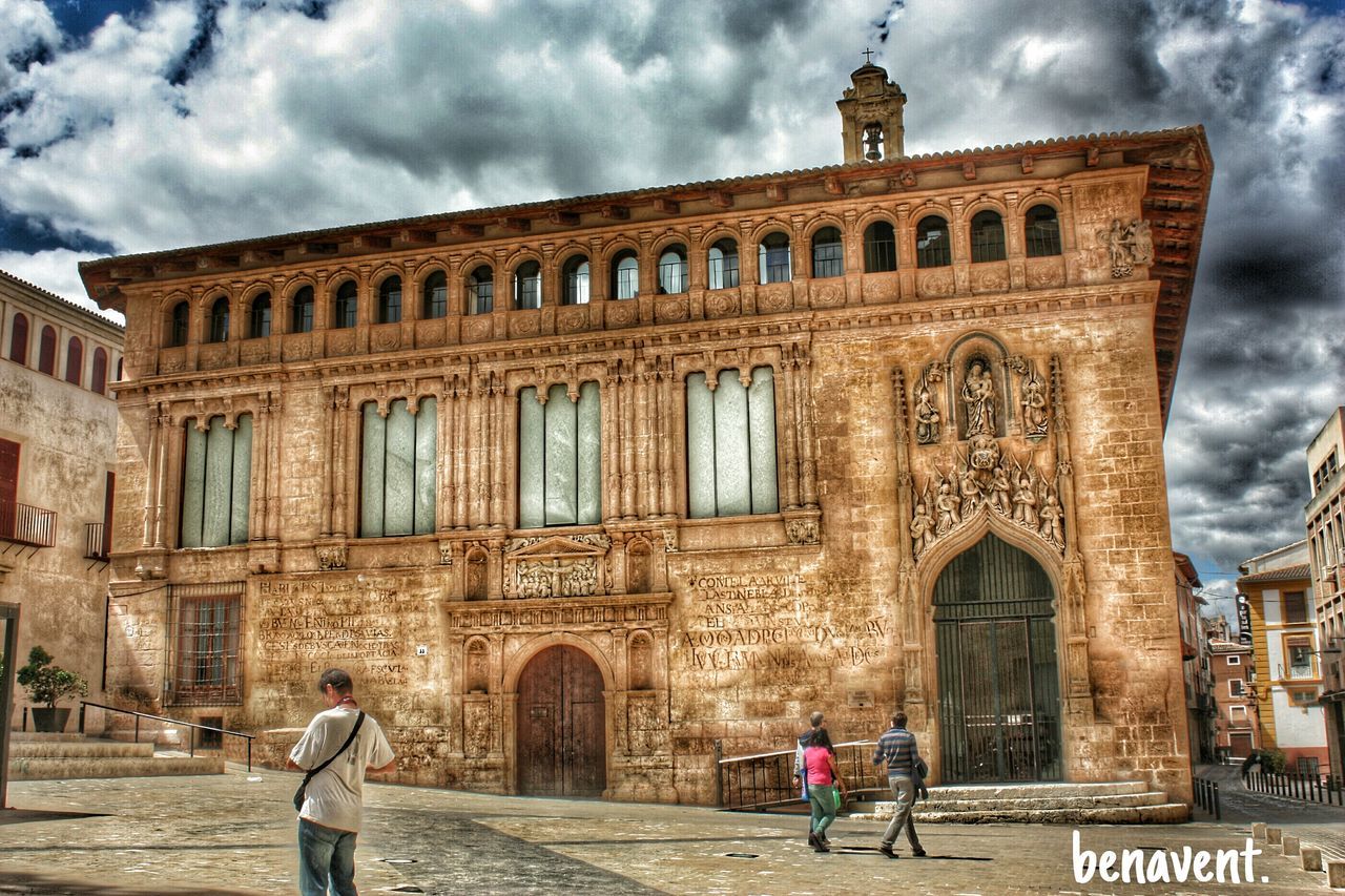 TOURISTS AGAINST CLOUDY SKY