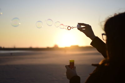 Scenic view of person blowing bubbles in air against clear sky