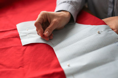 Working with a pattern in close-up, the hands of the skilled worker trace the pattern with chalk