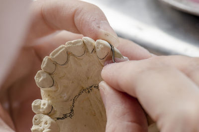 Cropped hands of person working on dentures