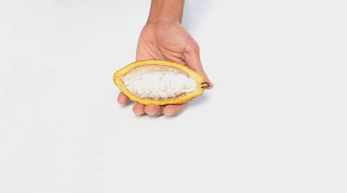 Close-up of hand holding ice cream over white background