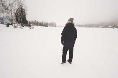 Rear view of man standing on snow covered field