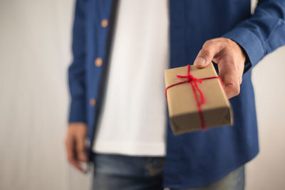 Midsection of man holding paper while standing against wall