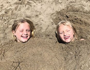 Portrait of smiling girls buried in sand