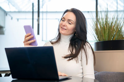 Young woman using laptop while sitting on sofa at home