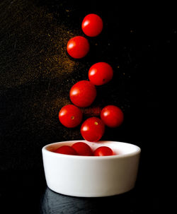 Close-up of tomatoes in bowl against black background